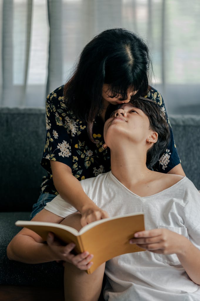 A loving couple shares a quiet moment reading on a cozy couch indoors.