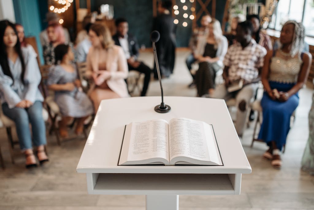 A microphone and open book on a podium in front of an audience in a church setting.