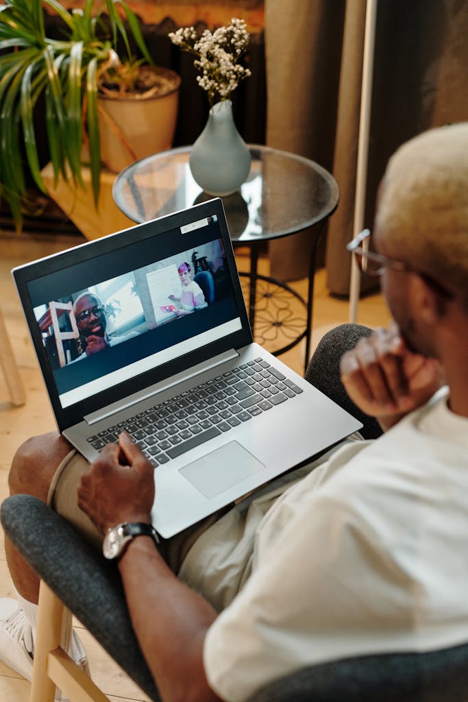 A person participating in a video call on a laptop at home with houseplants in the background.