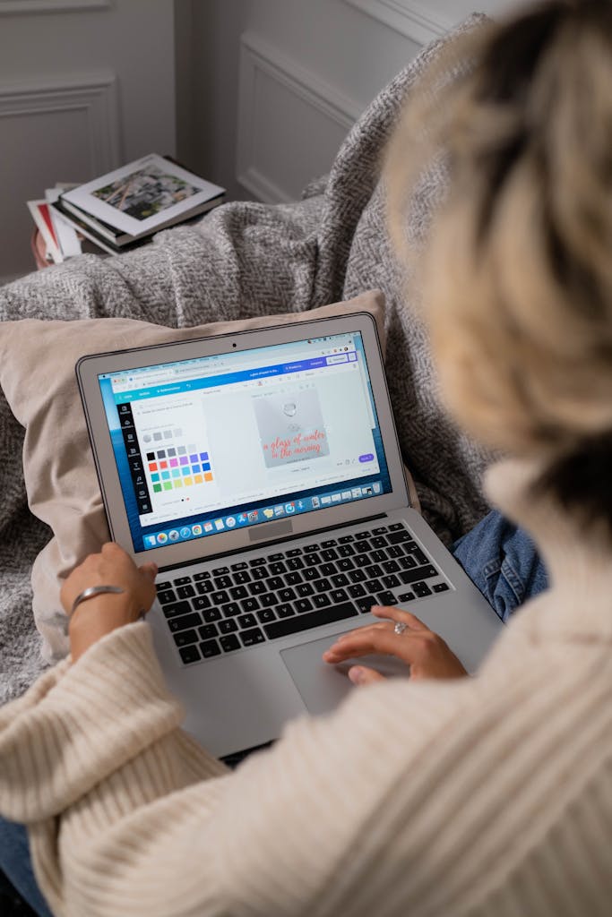 Woman working on design software from home on a comfortable couch.
